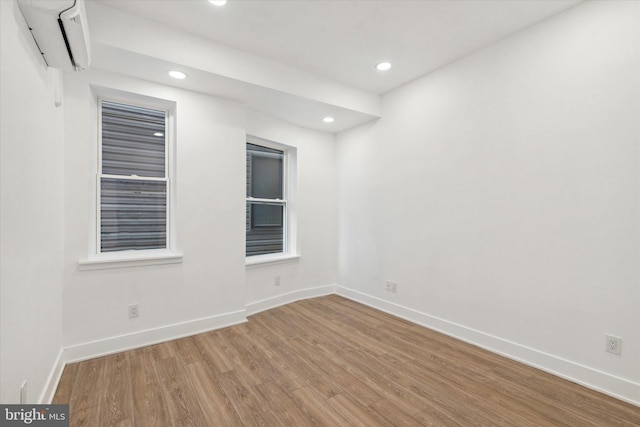 empty room featuring a wall mounted AC and wood-type flooring