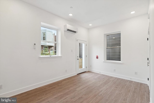 empty room with a wall mounted air conditioner and light wood-type flooring