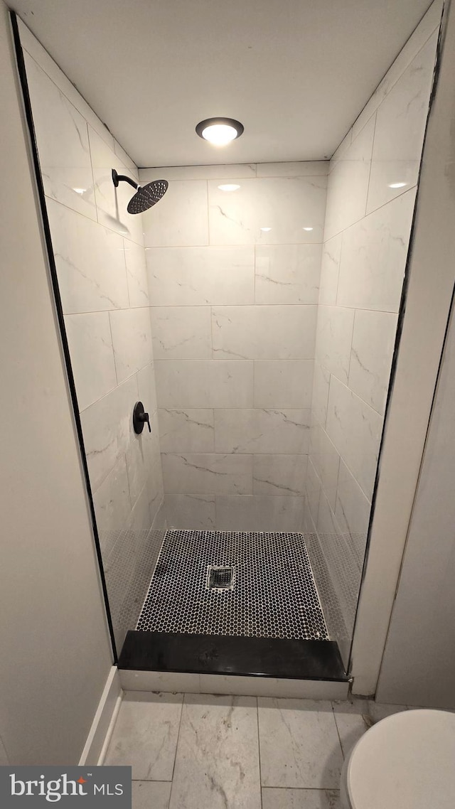 bathroom with a tile shower and toilet