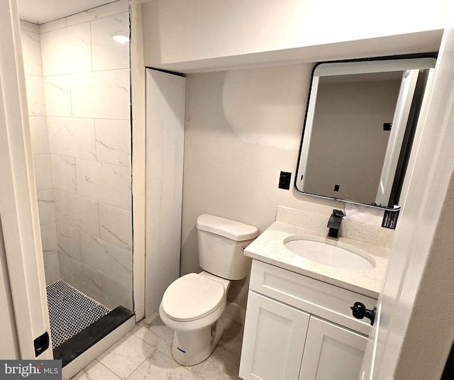 bathroom with toilet, a tile shower, and vanity