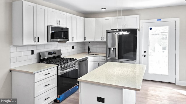 kitchen featuring light hardwood / wood-style flooring, sink, white cabinetry, a kitchen island, and stainless steel appliances