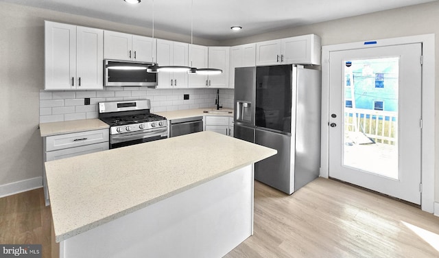 kitchen with white cabinetry, light wood-type flooring, stainless steel appliances, a kitchen island, and decorative backsplash