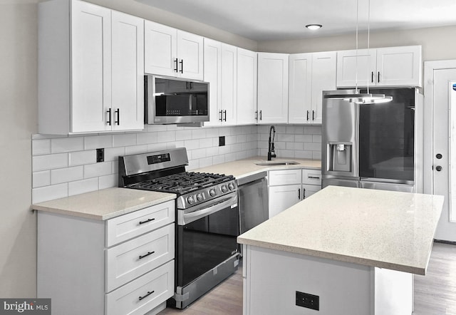 kitchen with white cabinets, stainless steel appliances, a kitchen island, and sink