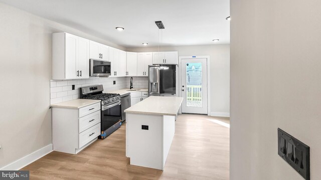 kitchen featuring a kitchen island, stainless steel appliances, white cabinetry, and decorative light fixtures