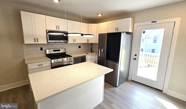 kitchen featuring white cabinets, a center island, stainless steel appliances, and sink