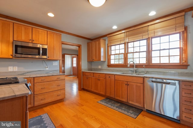 kitchen with light hardwood / wood-style floors, crown molding, sink, and appliances with stainless steel finishes