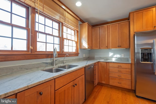 kitchen featuring light stone countertops, appliances with stainless steel finishes, light hardwood / wood-style floors, and sink