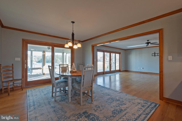 dining room with ceiling fan with notable chandelier, light hardwood / wood-style floors, and crown molding