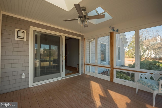 unfurnished sunroom with ceiling fan, a wealth of natural light, and a skylight