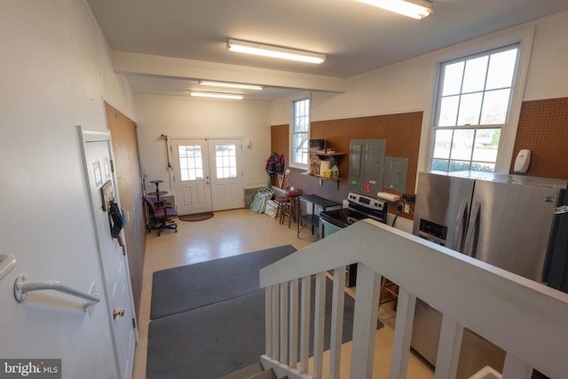 interior space featuring range with electric cooktop, french doors, stainless steel fridge with ice dispenser, electric panel, and concrete flooring