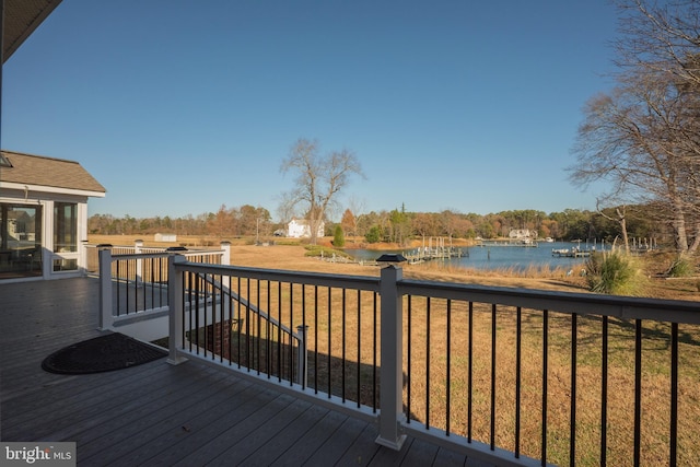 wooden terrace featuring a water view and a lawn