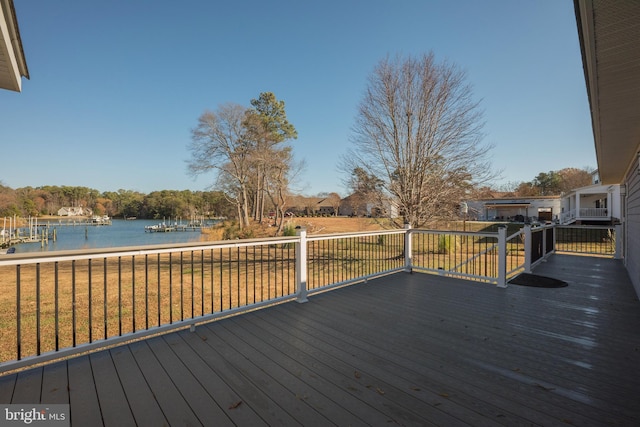 wooden terrace with a water view and a yard