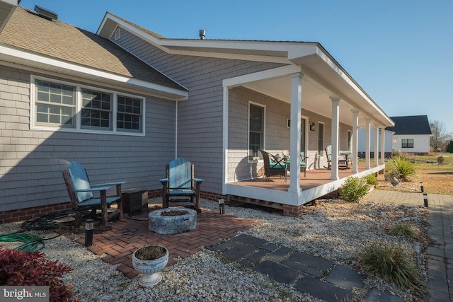 rear view of house with covered porch and an outdoor fire pit