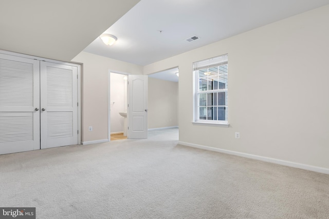 unfurnished bedroom featuring light colored carpet, connected bathroom, and a closet