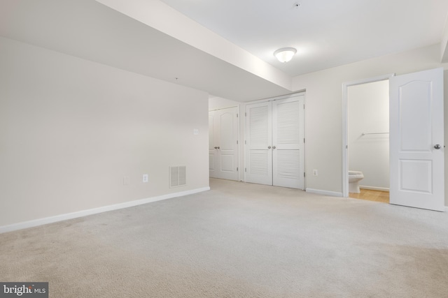 unfurnished bedroom featuring ensuite bath and light carpet