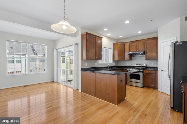 kitchen with sink, stainless steel appliances, light wood-type flooring, and hanging light fixtures