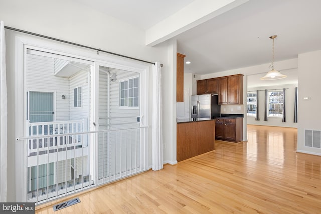 kitchen featuring tasteful backsplash, light hardwood / wood-style flooring, stainless steel fridge, pendant lighting, and beam ceiling