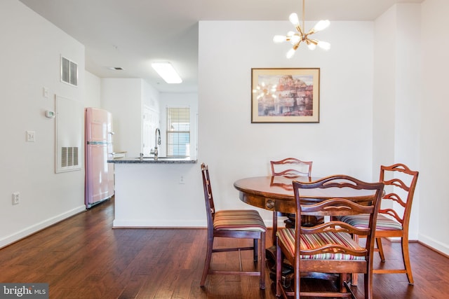 dining space with sink, a chandelier, and dark hardwood / wood-style floors