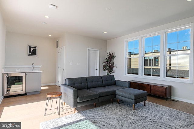 living room featuring indoor wet bar, light wood-type flooring, and wine cooler