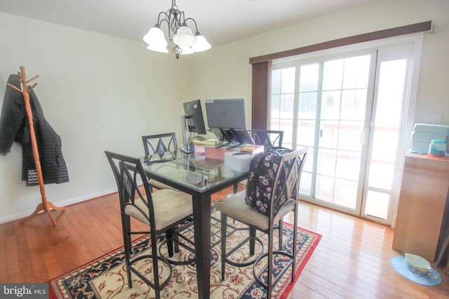 dining area with light hardwood / wood-style flooring and an inviting chandelier