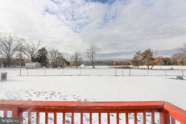 yard layered in snow featuring a storage shed