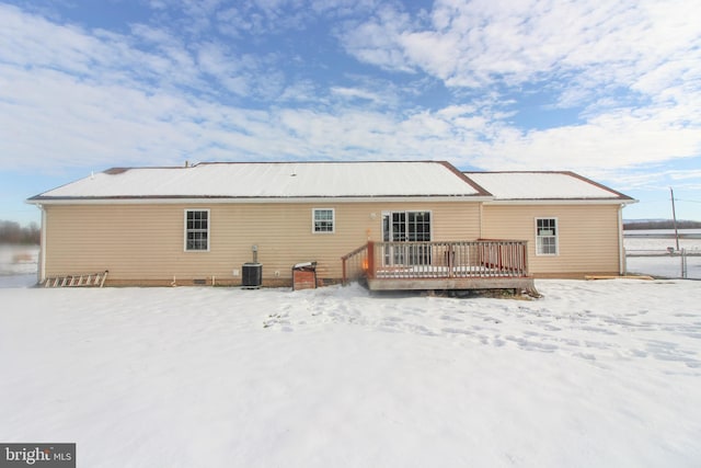 snow covered house featuring central AC unit and a deck