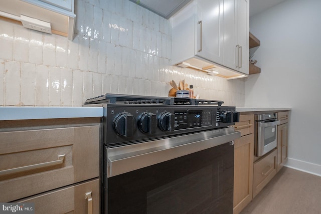 kitchen featuring decorative backsplash, light hardwood / wood-style floors, white cabinetry, and appliances with stainless steel finishes