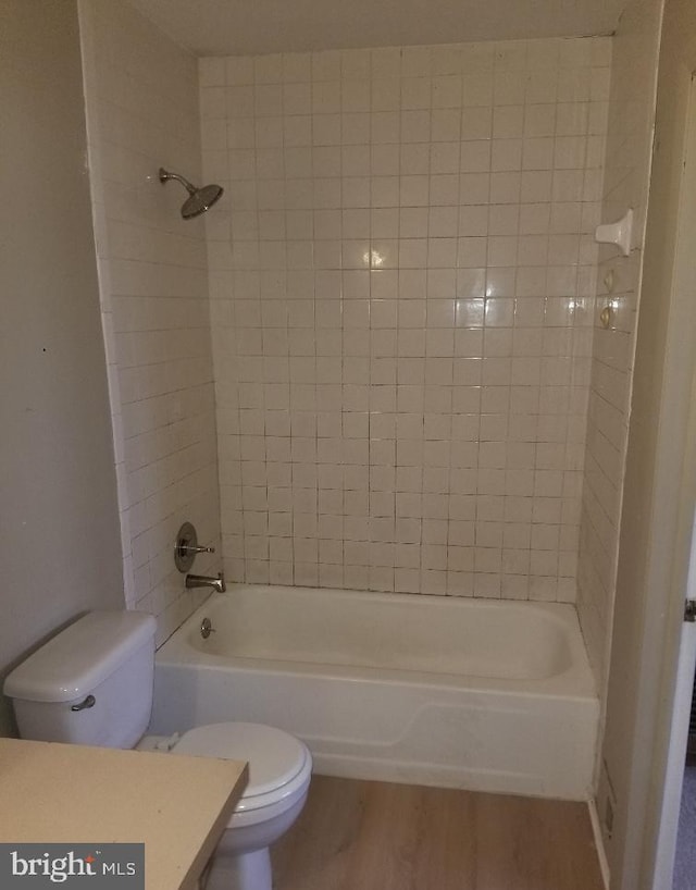 bathroom featuring hardwood / wood-style floors, tiled shower / bath combo, and toilet