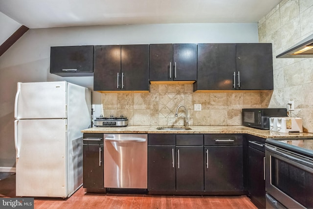 kitchen featuring sink, decorative backsplash, light stone countertops, light wood-type flooring, and stainless steel appliances