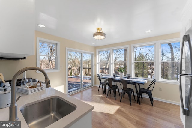 kitchen featuring stainless steel fridge, sink, white cabinets, and light hardwood / wood-style flooring