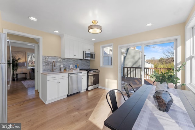 kitchen with white cabinetry, sink, tasteful backsplash, appliances with stainless steel finishes, and light wood-type flooring