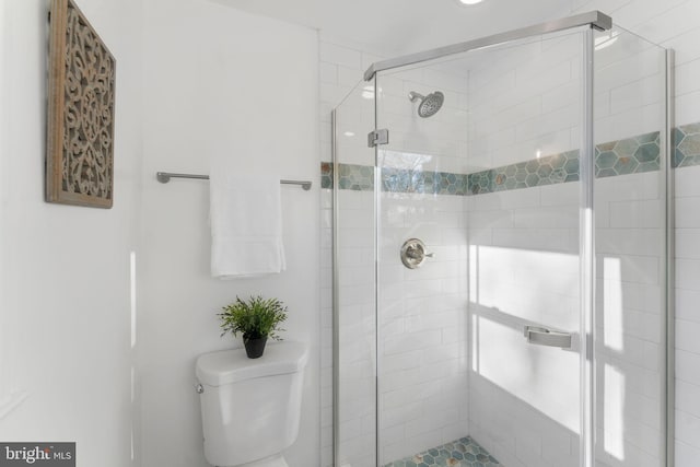 bathroom featuring toilet and a shower with shower door