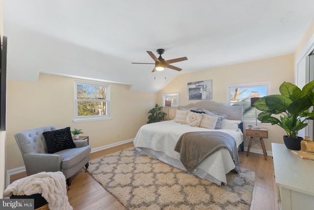 bedroom featuring ceiling fan, vaulted ceiling, light wood-type flooring, and multiple windows