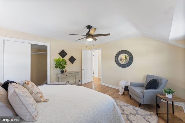 bedroom with a closet, light hardwood / wood-style floors, ceiling fan, and lofted ceiling