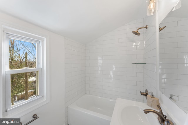 bathroom featuring sink, lofted ceiling, and tiled shower / bath