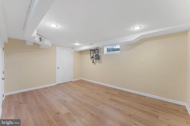 basement featuring light wood-type flooring and brick wall