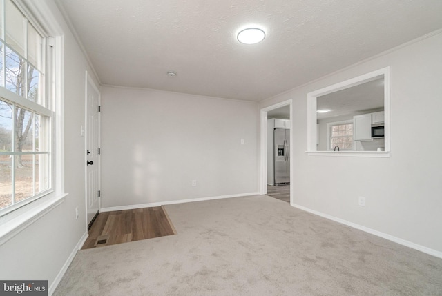 carpeted spare room featuring crown molding, plenty of natural light, and a textured ceiling