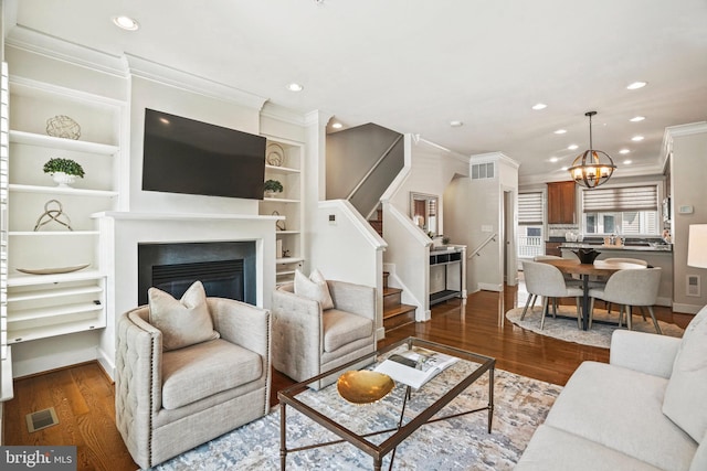 living room featuring a notable chandelier, crown molding, built in features, and dark wood-type flooring