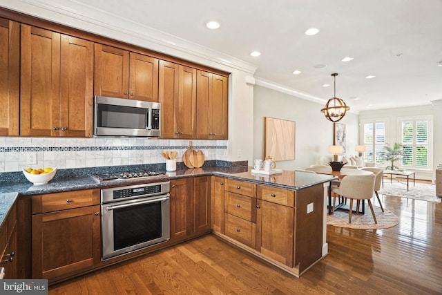 kitchen featuring hanging light fixtures, kitchen peninsula, crown molding, and appliances with stainless steel finishes