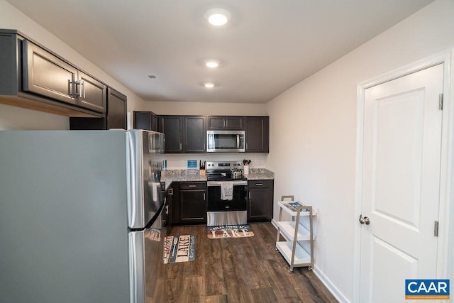 kitchen featuring dark hardwood / wood-style floors, light stone counters, and stainless steel appliances