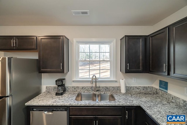 kitchen featuring light stone counters, sink, stainless steel appliances, and dark brown cabinets