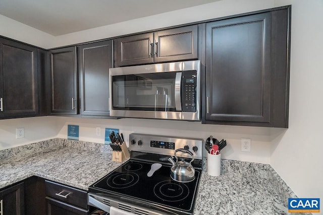 kitchen with light stone countertops, appliances with stainless steel finishes, and dark brown cabinets