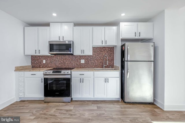 kitchen with sink, white cabinets, light hardwood / wood-style floors, and appliances with stainless steel finishes