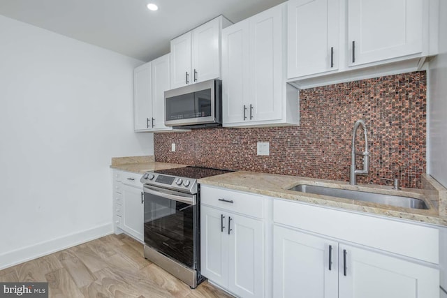 kitchen with decorative backsplash, light wood-type flooring, stainless steel appliances, sink, and white cabinets