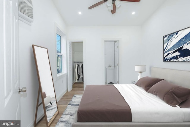 bedroom featuring ceiling fan, a spacious closet, a wall mounted air conditioner, light hardwood / wood-style flooring, and a closet