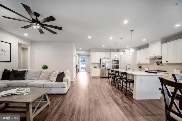 living room featuring dark hardwood / wood-style flooring, ceiling fan, and sink