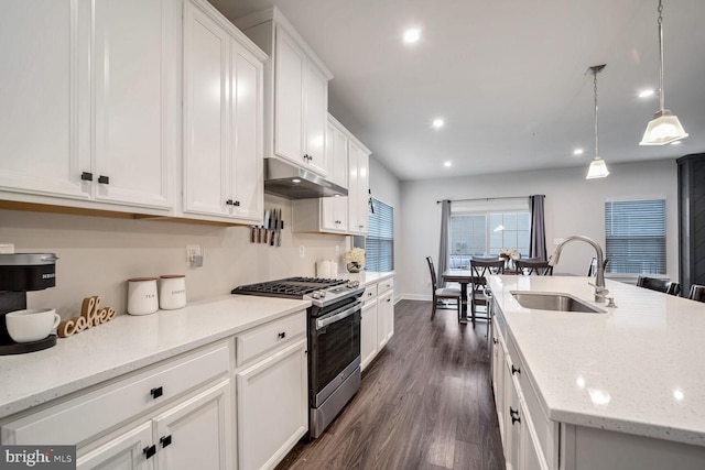 kitchen featuring a center island with sink, sink, hanging light fixtures, white cabinetry, and stainless steel range with gas stovetop