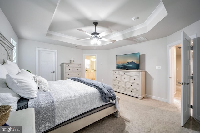 bedroom with light carpet, connected bathroom, a tray ceiling, and ceiling fan