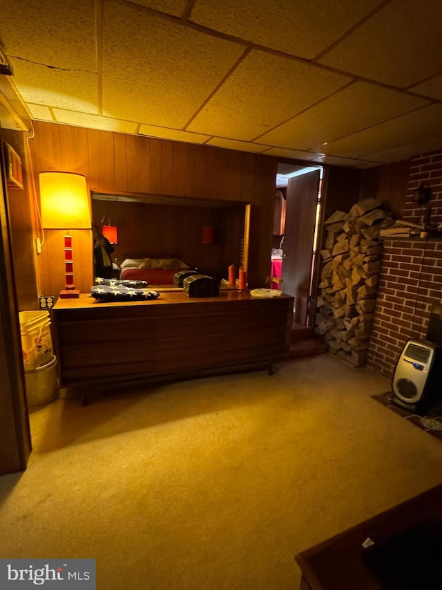 interior space featuring carpet flooring, a paneled ceiling, and wooden walls