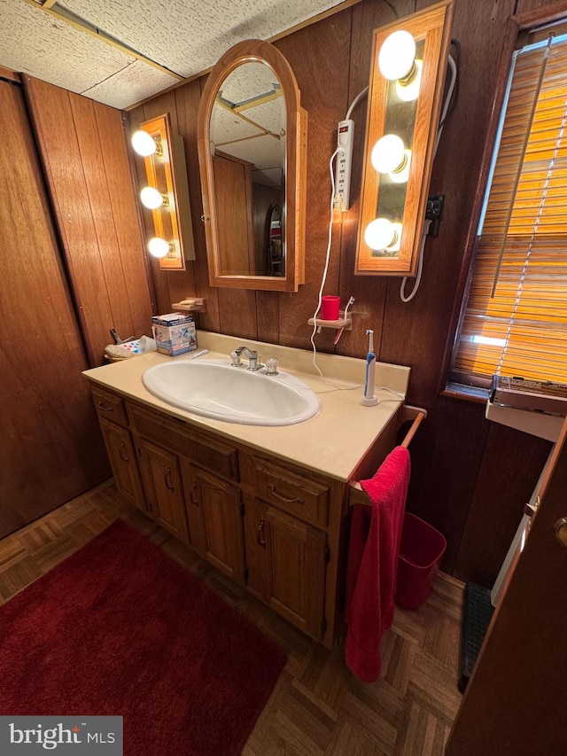 bathroom featuring vanity, wood walls, and parquet flooring